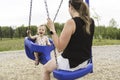 Cute baby girl playing on outdoor playground with mother on swing Royalty Free Stock Photo