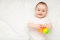 Cute baby girl playing with rattle on bed with copy space Royalty Free Stock Photo