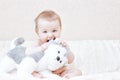 Cute baby girl playing with soft toy on bed in bedroom Royalty Free Stock Photo