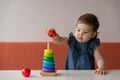 Baby girl playing with wooden colourful toy pyramid at home. Royalty Free Stock Photo