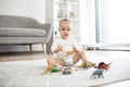 Cute baby girl posing with toy animals on floor indoors Royalty Free Stock Photo