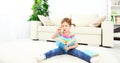 Cute baby girl reading book at home sitting on floor Royalty Free Stock Photo