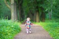 Cute baby girl in rubber rain boots walking in rainy park Royalty Free Stock Photo