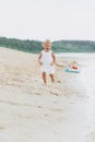 Cute baby girl runing and having fun on the beach near lake. The concept of summer holiday. baby`s day. Family spending