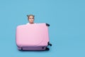 Cute baby girl sitting in a suitcase and waiting for summer vacation after quarantine. Pointing to the side. Royalty Free Stock Photo