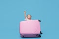 Cute baby girl sitting in a suitcase and waiting for summer vacation after quarantine. Pointing to the side. Royalty Free Stock Photo