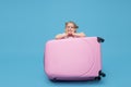 Cute baby girl sitting in a suitcase and waiting for summer vacation after quarantine. Pointing to the side. Royalty Free Stock Photo