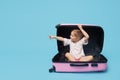 Cute baby girl sitting in a suitcase and waiting for summer vacation after quarantine. Pointing to the side. Royalty Free Stock Photo