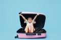 Cute baby girl sitting in a suitcase and waiting for summer vacation after quarantine. Pointing to the side. Royalty Free Stock Photo