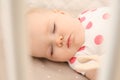 Cute baby girl sleeping in crib, closeup. Bedtime