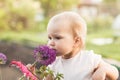 Cute baby girl smelling purple Allium flower in the garden Royalty Free Stock Photo