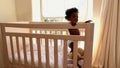 Cute baby girl standing in her crib looking at camera