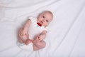 Cute baby girl stares into the camera. Newborn in diapers on white sheets. Top view