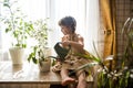 A cute baby girl takes care of houseplants. Girl watering and spraying indoor plants at home Royalty Free Stock Photo