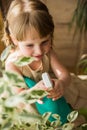 A cute baby girl takes care of houseplants. Girl watering and spraying indoor plants at home Royalty Free Stock Photo