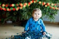 Cute baby girl taking down holiday decorations from Christmas tree. child holding light garland. Family after Royalty Free Stock Photo