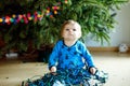 Cute baby girl taking down holiday decorations from Christmas tree. child holding light garland. Family after Royalty Free Stock Photo