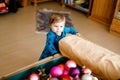 Cute baby girl taking down holiday decorations from Christmas tree. child holding light garland. Family after Royalty Free Stock Photo
