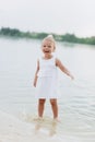 Cute baby girl walking and having fun on the beach near lake. The concept of summer holiday. baby`s day. Family spending time