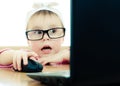 Cute baby with glasses looking into the laptop Royalty Free Stock Photo