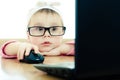 Cute baby with glasses looking into the laptop Royalty Free Stock Photo