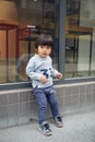 Cute baby in gray suit and green shoes standing and posing in front of glass door Royalty Free Stock Photo