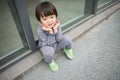 Cute baby in gray suit and green shoes standing and posing in front of glass door Royalty Free Stock Photo