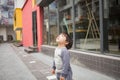 Cute baby in gray suit and green shoes standing and posing in front of glass door Royalty Free Stock Photo