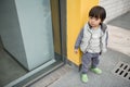 Cute baby in gray suit and green shoes standing and posing in front of glass door Royalty Free Stock Photo