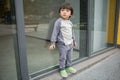 Cute baby in gray suit and green shoes standing and posing in front of glass door Royalty Free Stock Photo