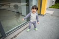 Cute baby in gray suit and green shoes standing and posing in front of glass door Royalty Free Stock Photo