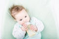 Cute baby in a green sweater drinking milk from a bottle Royalty Free Stock Photo