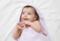 Cute little baby in hooded towel after bathing nibbling teether on bed, top view Royalty Free Stock Photo