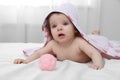 Cute little baby in hooded towel after bathing playing with toy on bed at home Royalty Free Stock Photo