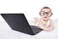 Cute baby with laptop and glasses on bed Royalty Free Stock Photo