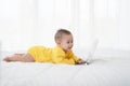 Cute baby with laptop on the white bed