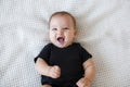 Cute baby lies and crawls on a white bed in a bright bedroom alone. Royalty Free Stock Photo