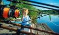 Cute baby little boy fishing with fishing road in lake from wooden dock. Royalty Free Stock Photo