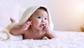 Cute baby looking at camera under white blanket looking at something. Innocence baby crawling on white bed with towel on Royalty Free Stock Photo