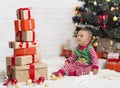 Cute baby looking at high heap of present boxes