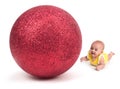 Cute Baby looking at a Huge Christmas Ornament on white