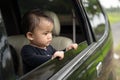 Cute baby looks outside while standing in the car with the windows open