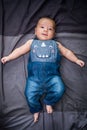 Cute baby lying in a bead wearing jean