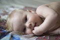 Cute baby lying on the bed with fingers in his mouth Royalty Free Stock Photo