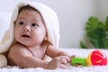 Cute baby lying on bed with toy under white blanket looking at something. Innocence baby crawling on white bed with towel Royalty Free Stock Photo