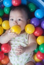 Cute baby lying in colorful toy balls and playing happily