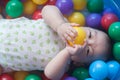 Cute baby lying in colorful toy balls and playing happily