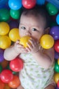 Cute baby lying in colorful toy balls and playing happily