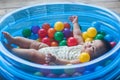 Cute baby lying in colorful toy balls and playing happily