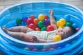 Cute baby lying in colorful toy balls and playing happily